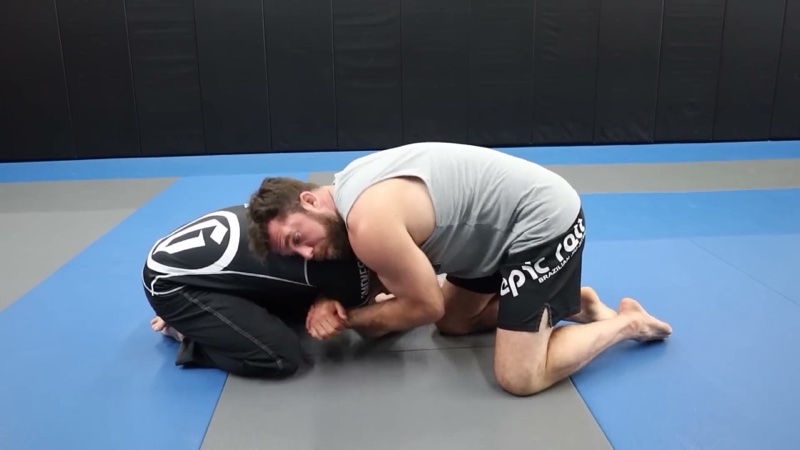 The attacker kneels in front of a snapped-down opponent, chest over the head, in a front headlock.