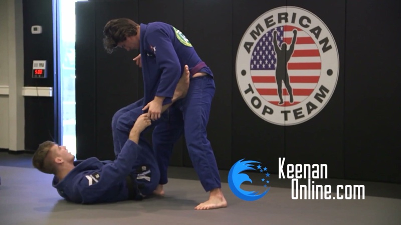 The bottom player wraps the standing opponent's lead leg while holding the gi lapel, in a worm-guard entry.